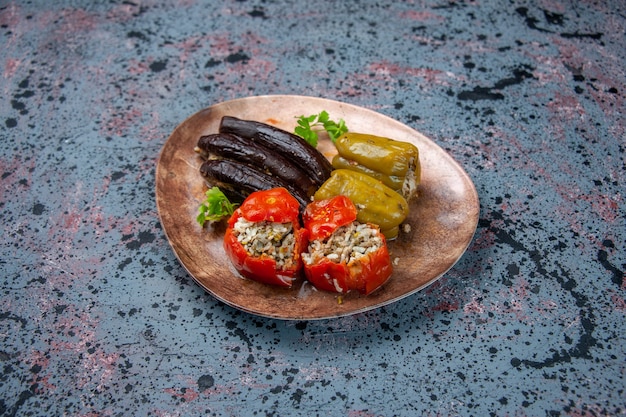 Vorderansicht Auberginen Dolma mit gekochten Tomaten und Paprika gefüllt mit Hackfleisch innerhalb Platte auf blauem Hintergrund