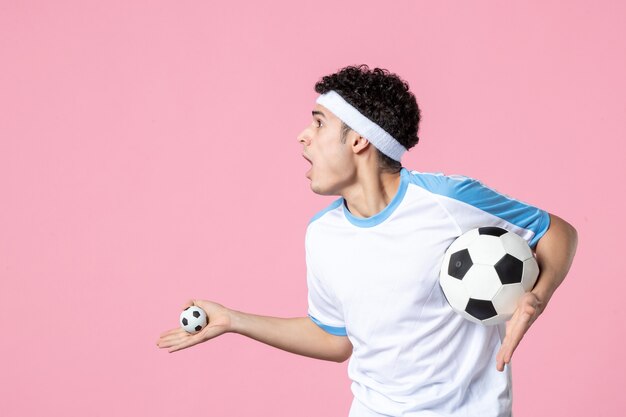 Vorderansicht aufgeregter Fußballspieler in Sportkleidung mit Ball