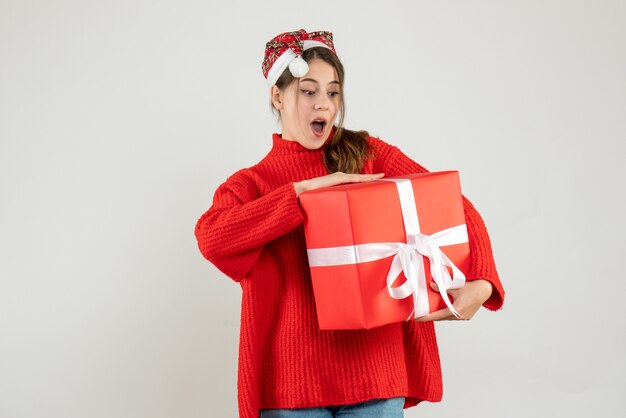 Vorderansicht aufgeregtes Mädchen mit Weihnachtsmütze, die Geschenk hält