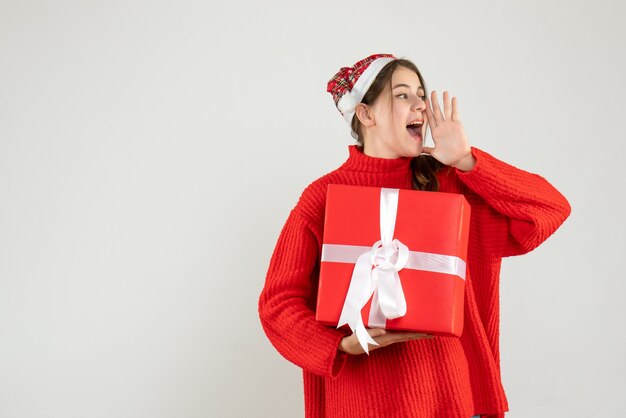 Vorderansicht aufgeregtes Mädchen mit Weihnachtsmütze, die Weihnachtsgeschenk hält, das jemanden anruft