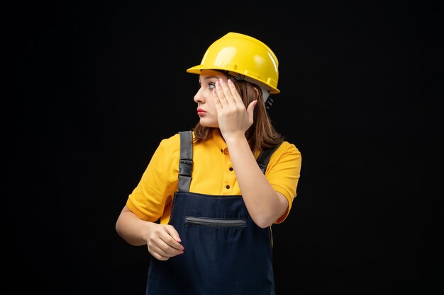 Vorderansicht Baumeisterin in Uniform und Helm an der schwarzen Wand