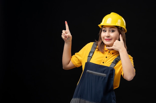 Vorderansicht Baumeisterin in Uniform und Helm an der schwarzen Wand