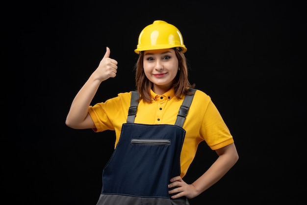 Vorderansicht Baumeisterin in Uniform und Helm an der schwarzen Wand