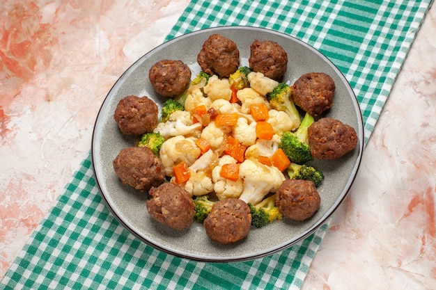 Vorderansicht Brokkoli- und Blumenkohlsalat und Fleischbällchen auf Teller grün-weiß karierte Serviette auf nacktem, isoliertem Hintergrund