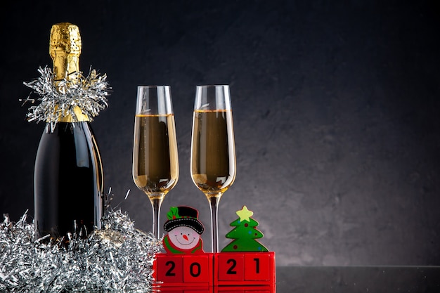 Vorderansicht Champagner in Flasche und Gläsern Holzblöcke auf dunkler Oberfläche
