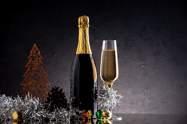Kostenloses Foto vorderansicht champagnerglasflasche weihnachtsschmuck auf dunkler oberfläche