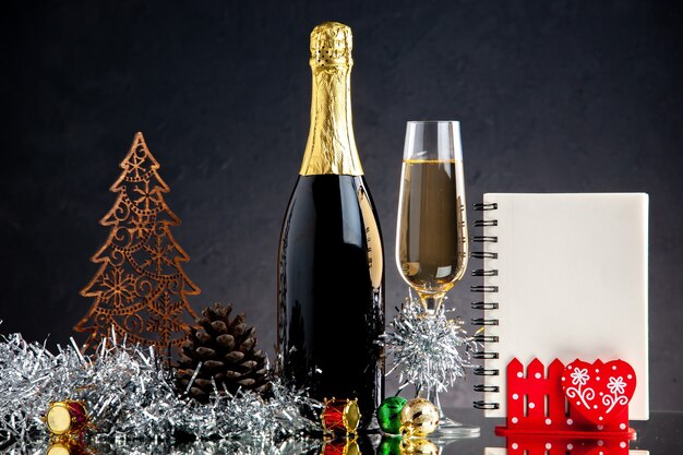 Vorderansicht Champagnerglasflasche Weihnachtsschmuck Notizbuch auf dunkler Oberfläche