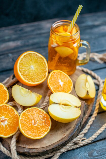 Vorderansicht Cocktail geschnittene Orangen und Äpfel auf Holzbrett auf dunkel