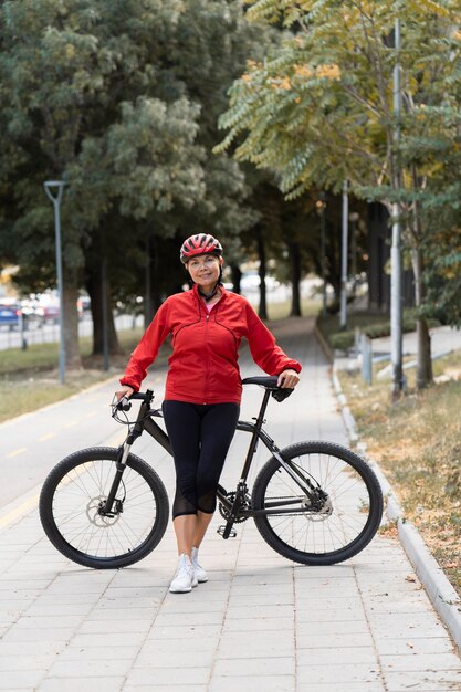 Vorderansicht der älteren Frau, die draußen mit Fahrrad aufwirft