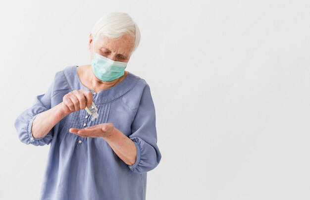 Vorderansicht der älteren Frau, die Händedesinfektionsmittel mit Kopienraum verwendet
