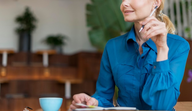 Vorderansicht der älteren Frau, die mit Stift arbeitet