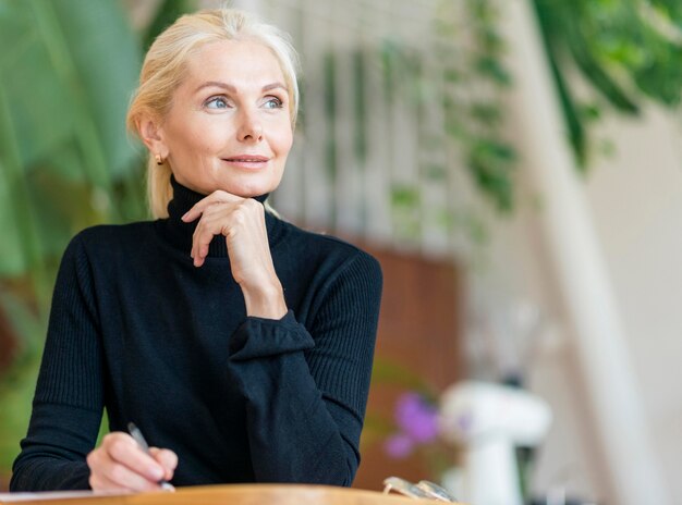 Vorderansicht der älteren Frau, die mit Stift arbeitet