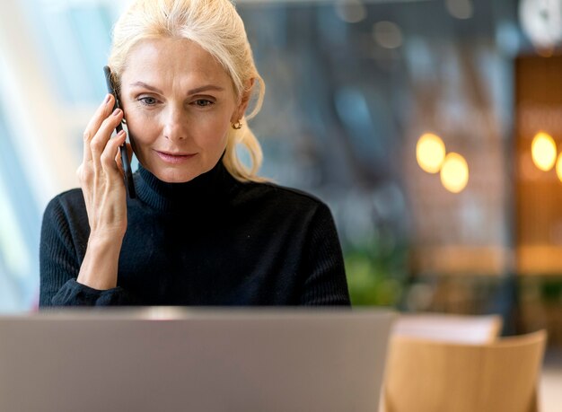 Vorderansicht der älteren Geschäftsfrau, die am Laptop arbeitet