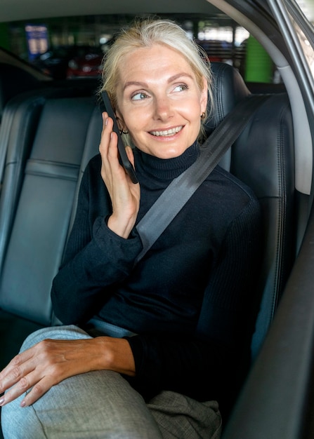 Kostenloses Foto vorderansicht der älteren geschäftsfrau, die das telefon im auto spricht