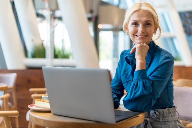 Vorderansicht der älteren Geschäftsfrau, die während der Arbeit am Laptop aufwirft