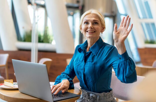 Vorderansicht der älteren Geschäftsfrau, die während der Arbeit am Laptop nach der Rechnung fragt