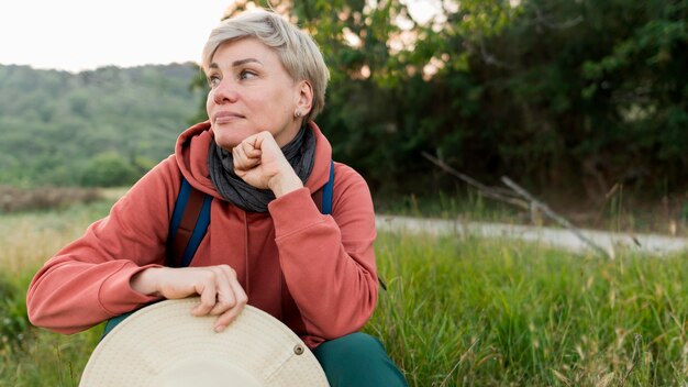 Vorderansicht der älteren Touristenfrau, die in der Natur aufwirft