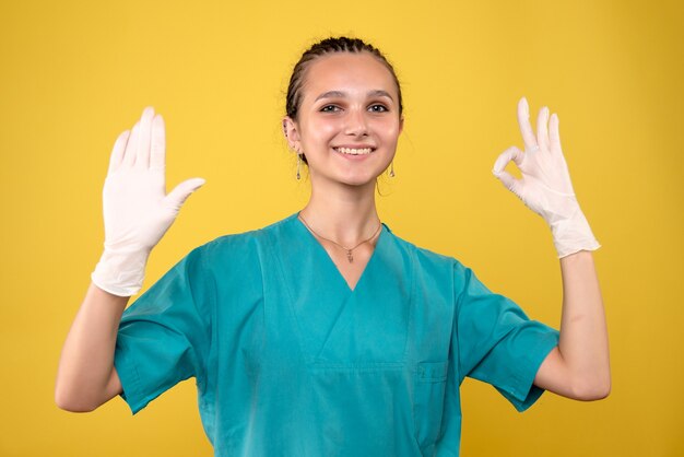 Vorderansicht der Ärztin, die spezielle Handschuhe auf gelber Wand trägt