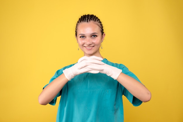 Kostenloses Foto vorderansicht der ärztin in speziellen handschuhen auf gelber wand