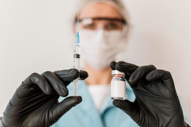 Vorderansicht der Ärztin mit Impfstoff und Handschuhen