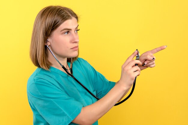 Vorderansicht der Ärztin mit Tonometer auf gelber Wand