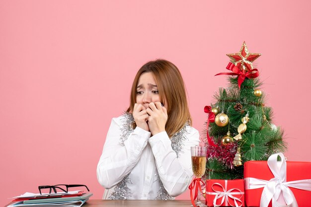 Vorderansicht der Arbeiterin, die um Weihnachtsgeschenke auf rosa sitzt