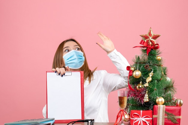 Vorderansicht der Arbeiterin in der Maske, die Aktennotiz auf Rosa hält