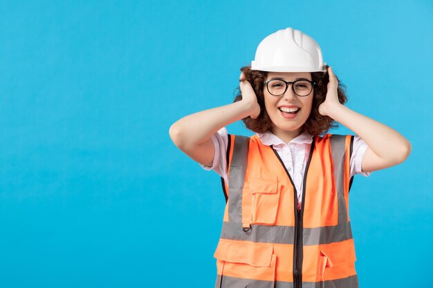 Vorderansicht der Arbeiterin in Uniform an der blauen Wand