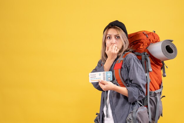 Vorderansicht der aufgeregten Reisendenfrau mit dem Rucksack, der Ticket hält
