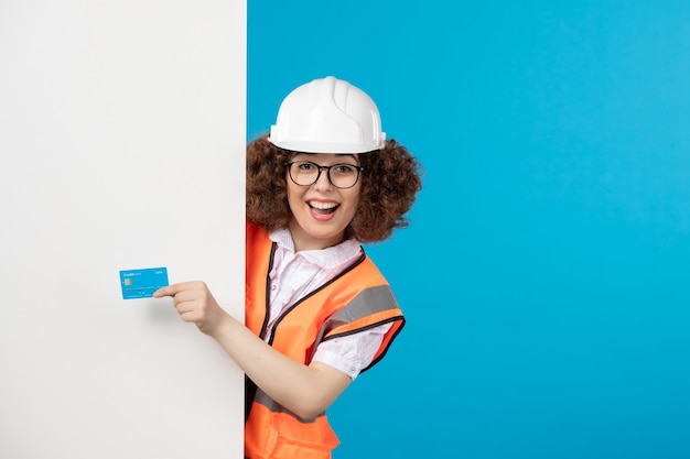 Vorderansicht der Baumeisterin in Uniform mit blauer Bankkarte auf blauer Wand