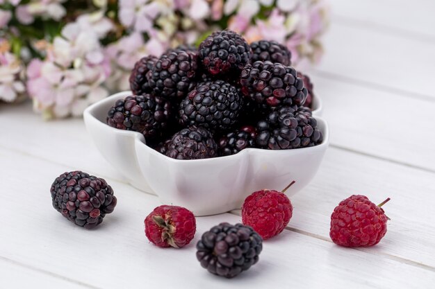 Vorderansicht der Brombeere mit Himbeeren in einer Schüssel auf einer weißen Oberfläche