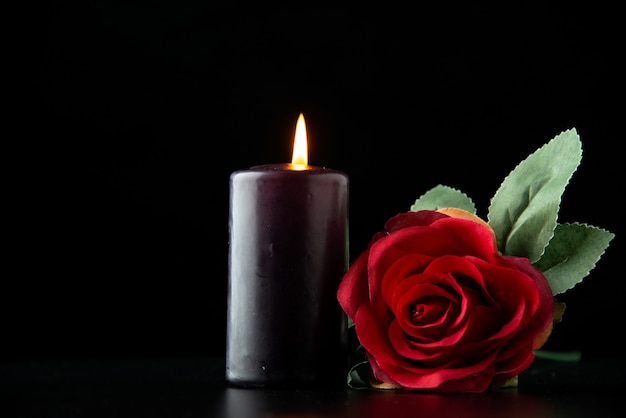 Vorderansicht der dunklen Kerze mit roter Rose auf der dunklen Oberfläche