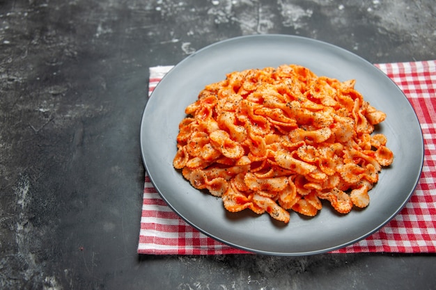 Vorderansicht der einfachen Pasta-Mahlzeit zum Abendessen auf einem schwarzen Teller auf einem rot gestreiften Handtuch to