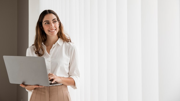 Vorderansicht der eleganten Geschäftsfrau des Smileys unter Verwendung des Laptops mit Kopienraum