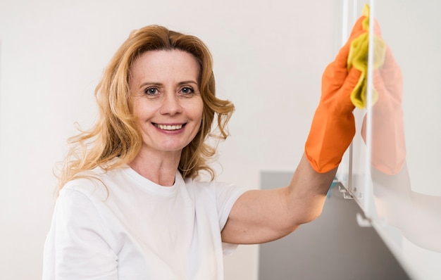 Kostenloses Foto vorderansicht der frau, die die küchenschränke reinigt