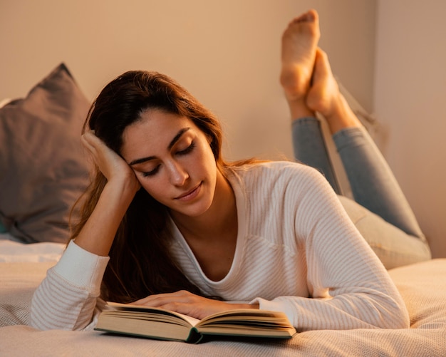 Kostenloses Foto vorderansicht der frau, die ein buch zu hause im bett liest