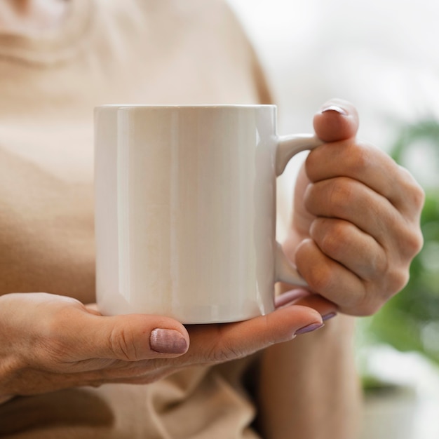 Vorderansicht der Frau, die einen Drink im Becher drinnen genießt