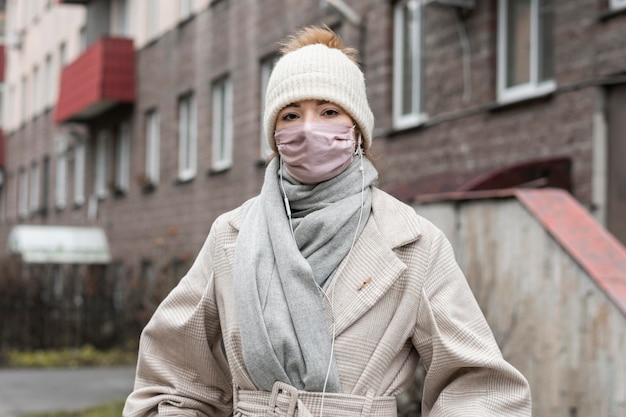 Vorderansicht der Frau, die medizinische Maske in der Stadt trägt