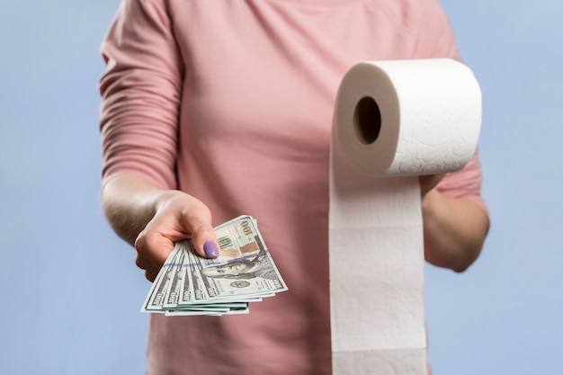 Kostenloses Foto vorderansicht der frau, die toilettenpapierrolle hält und geld anbietet