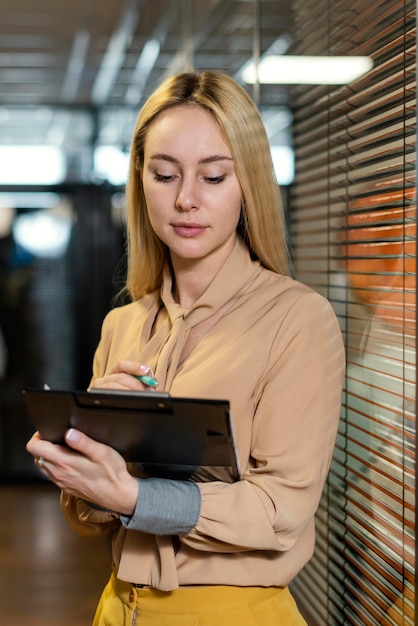 Kostenloses Foto vorderansicht der frau, die zwischenablage am arbeitsplatz hält