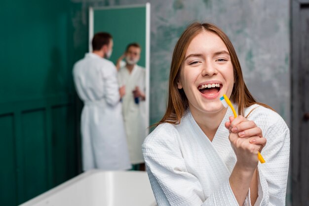 Vorderansicht der Frau im Bademantel singend in der Zahnbürste