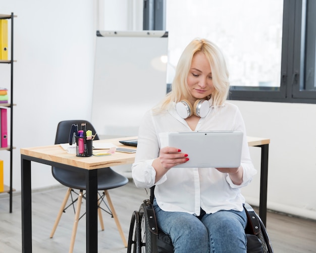 Kostenloses Foto vorderansicht der frau im rollstuhl am büro, das tablette hält