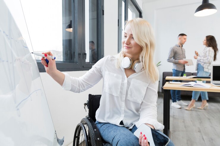 Kostenlose Foto vorderansicht der frau im rollstuhl, der auf whiteboard bei der arbeit schreibt