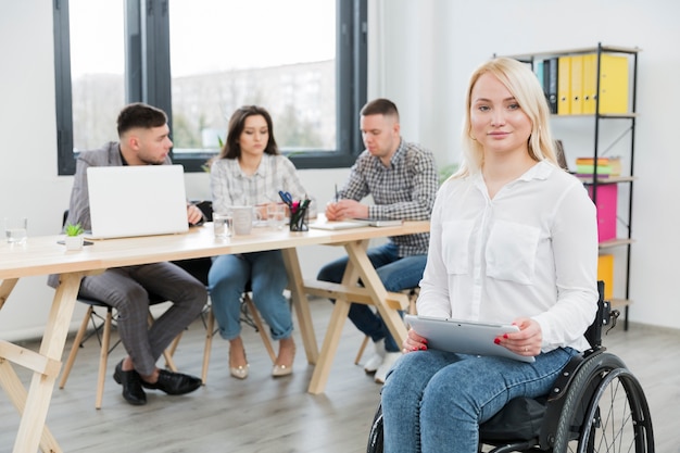 Kostenloses Foto vorderansicht der frau im rollstuhl, der im büro aufwirft