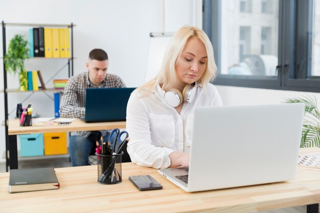 Vorderansicht der Frau im Rollstuhl, die von ihrem Schreibtisch im Büro arbeitet