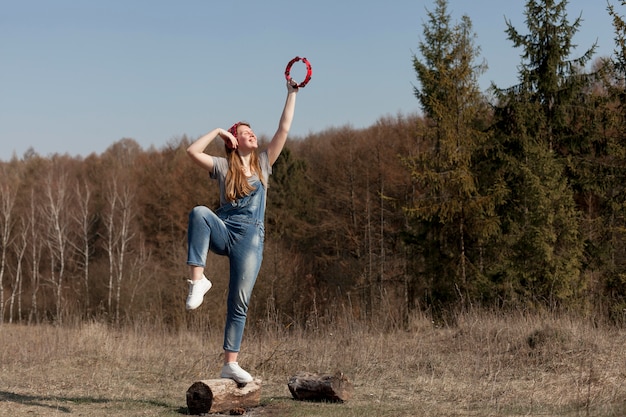 Kostenloses Foto vorderansicht der frau in der natur, die tamburin hält