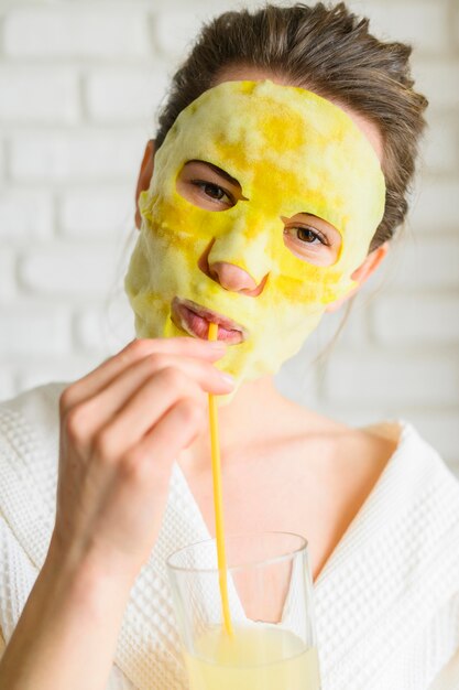 Vorderansicht der Frau mit Gesichtsmaske, die einen Drink genießt