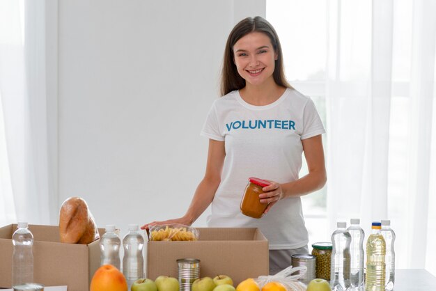 Vorderansicht der freiwilligen Helferin des Smileys, die mit Lebensmittelspenden hilft