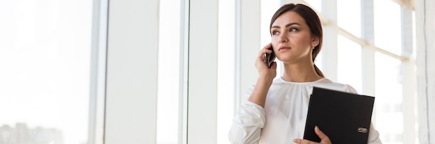 Vorderansicht der Geschäftsfrau, die am Telefon mit Kopienraum spricht