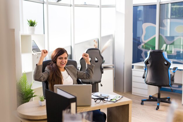 Vorderansicht der Geschäftsfrau, die im Büro siegreich ist